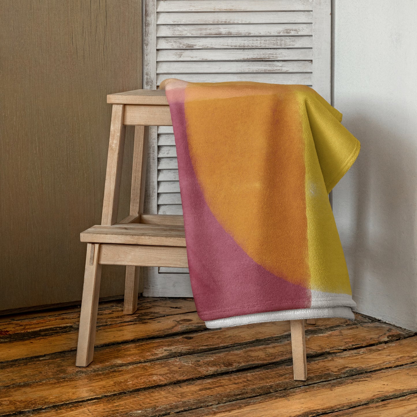 A beach towel with large abstract color blocks in mustard yellow, dusty pink, and olive green.