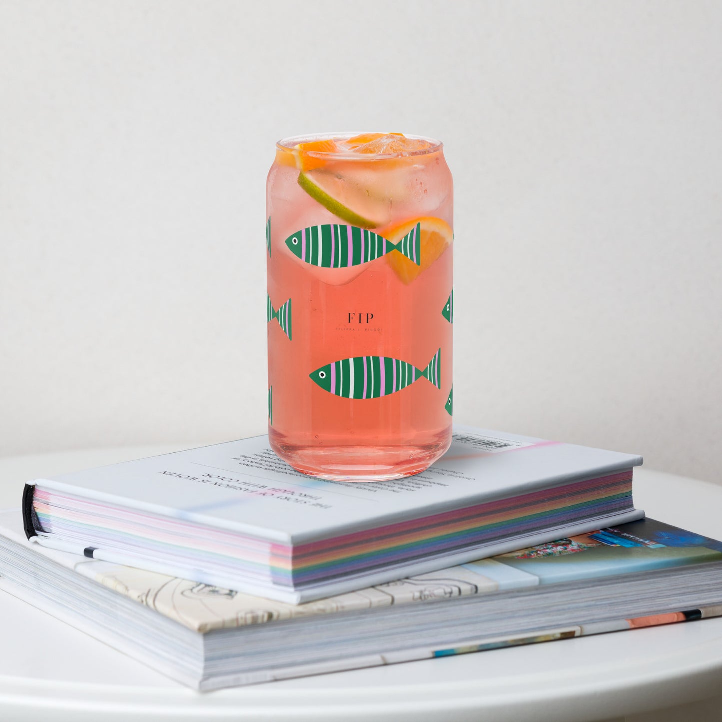 A clear glass can-shaped tumbler printed with green fish motifs.