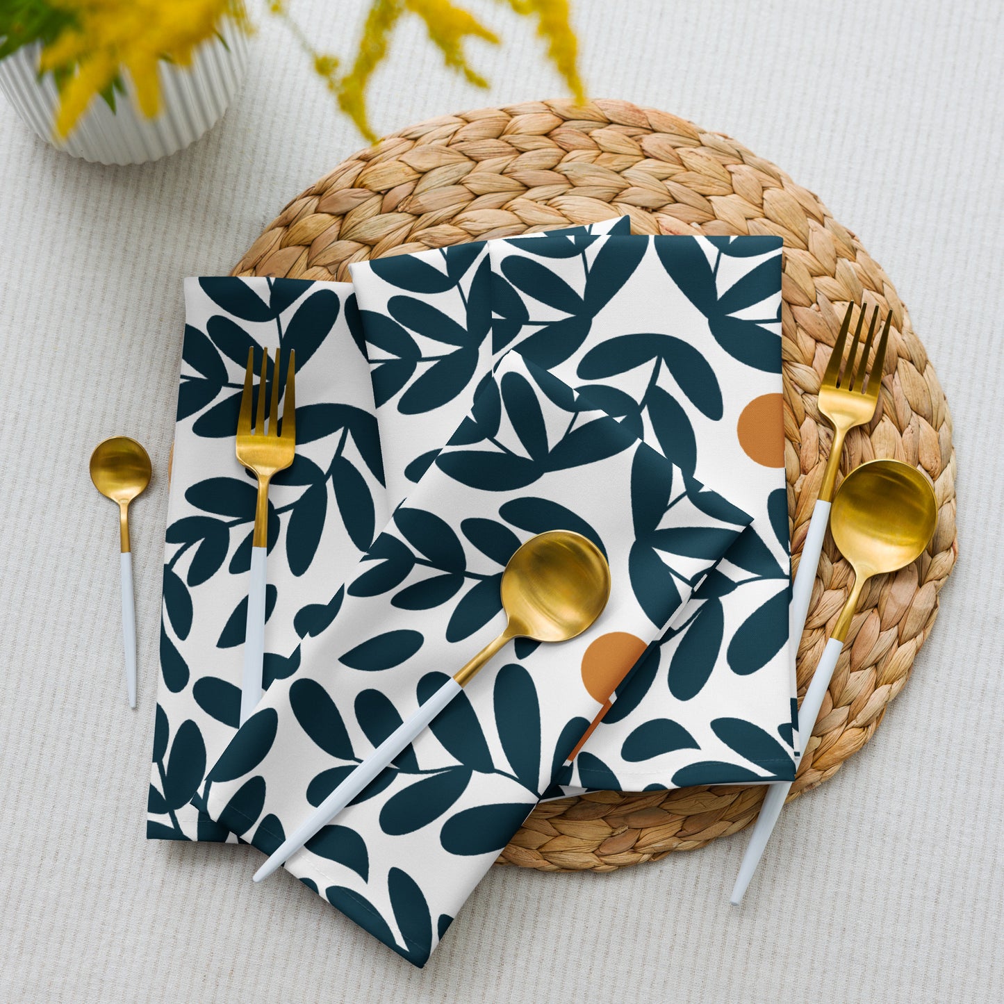 white cloth napkins with a dark teal leaf pattern and small yellow olives.