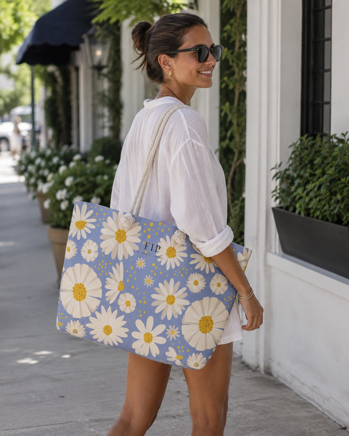 a large blue tote bag decorated with a white daisy floral pattern and yellow centers.