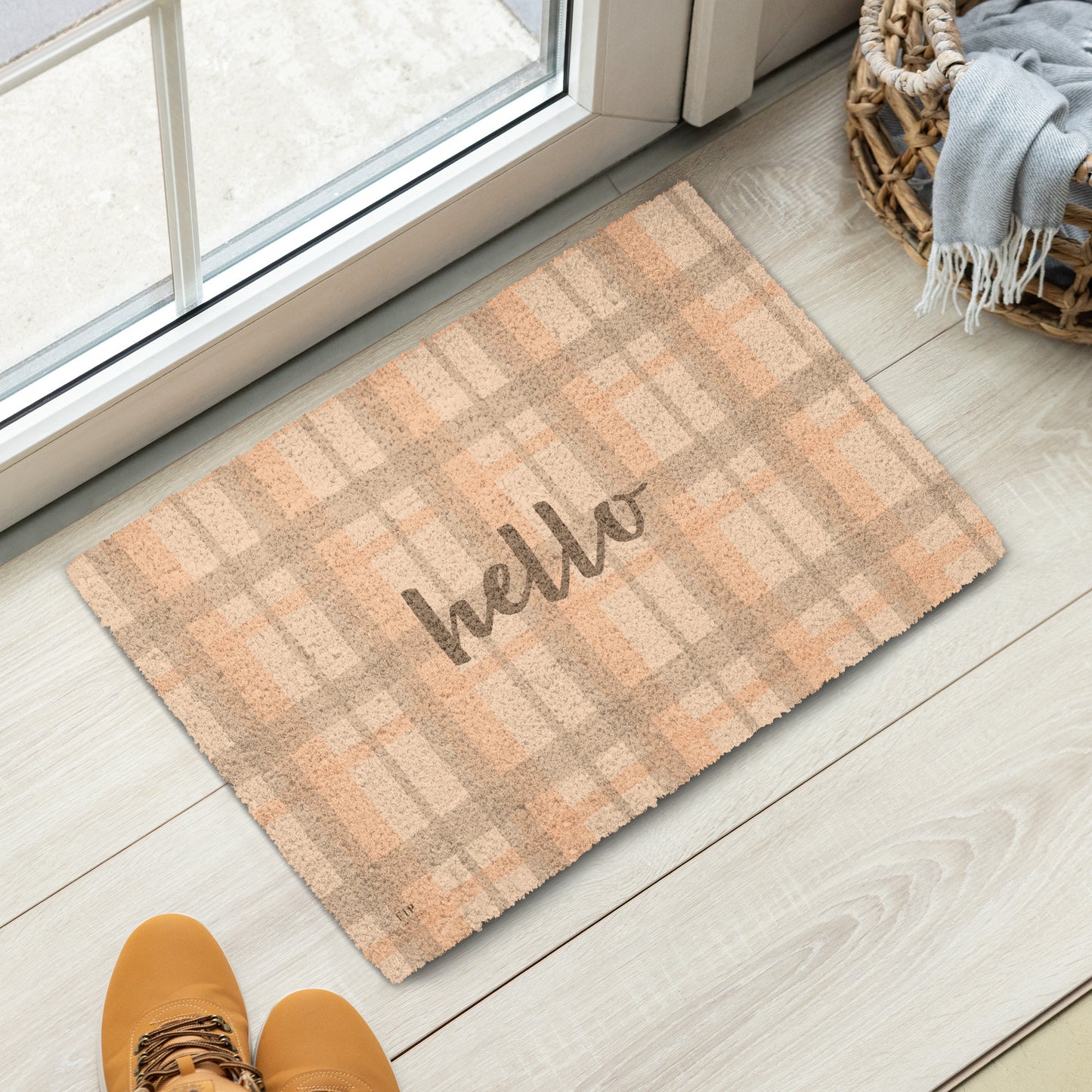 A rectangular coir doormat with a warm tan and peach plaid pattern and the word hello