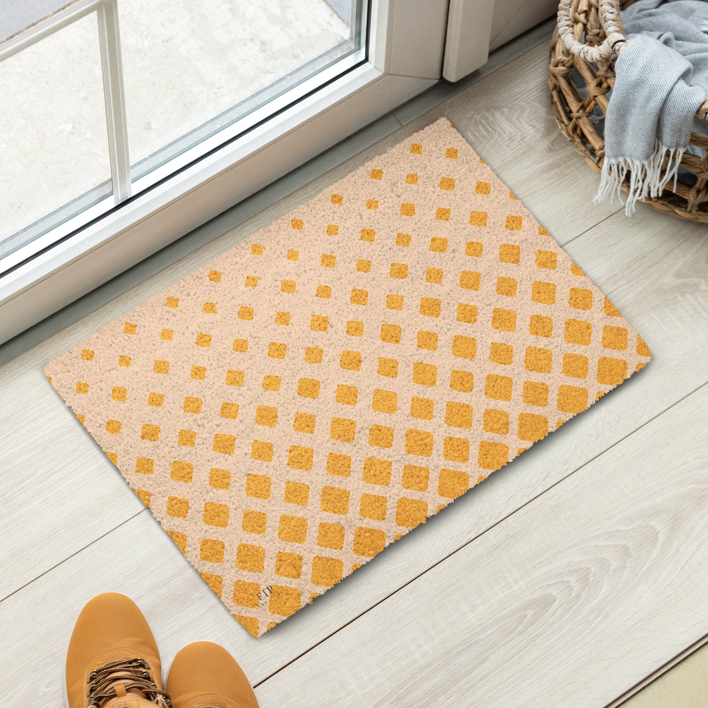 A rectangular doormat with a repeating yellow-orange geometric pattern on a light beige background