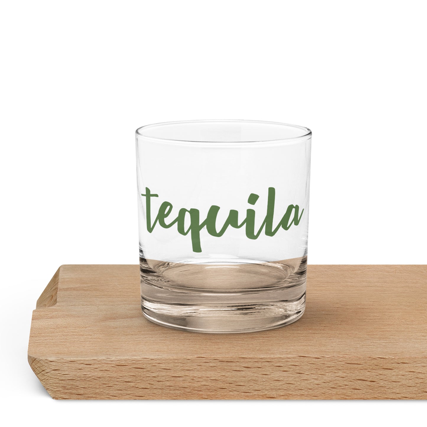 A clear rocks glass with the word 'tequila' printed in green script.