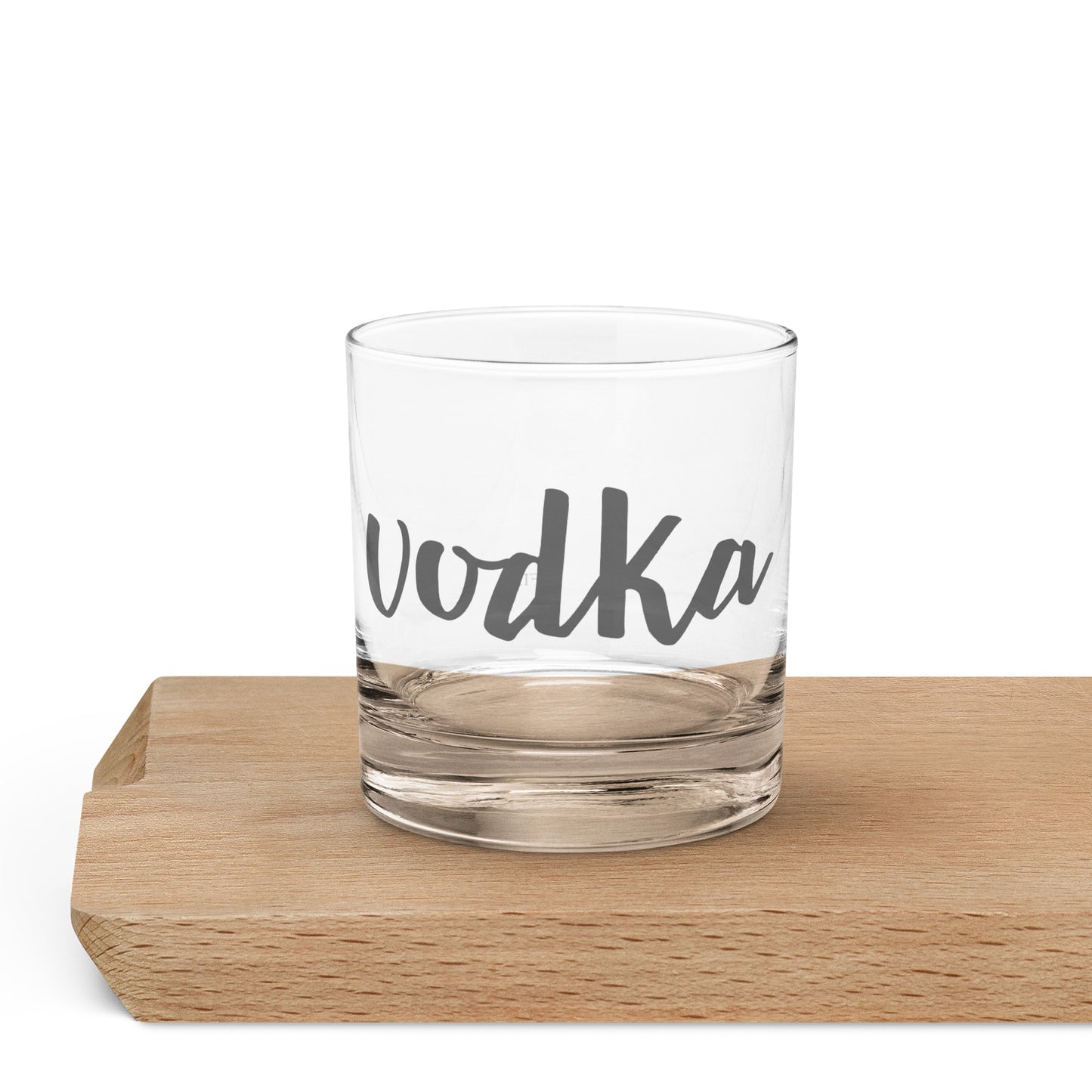 A clear glass rocks tumbler with the word 'vodka' printed in dark gray script.