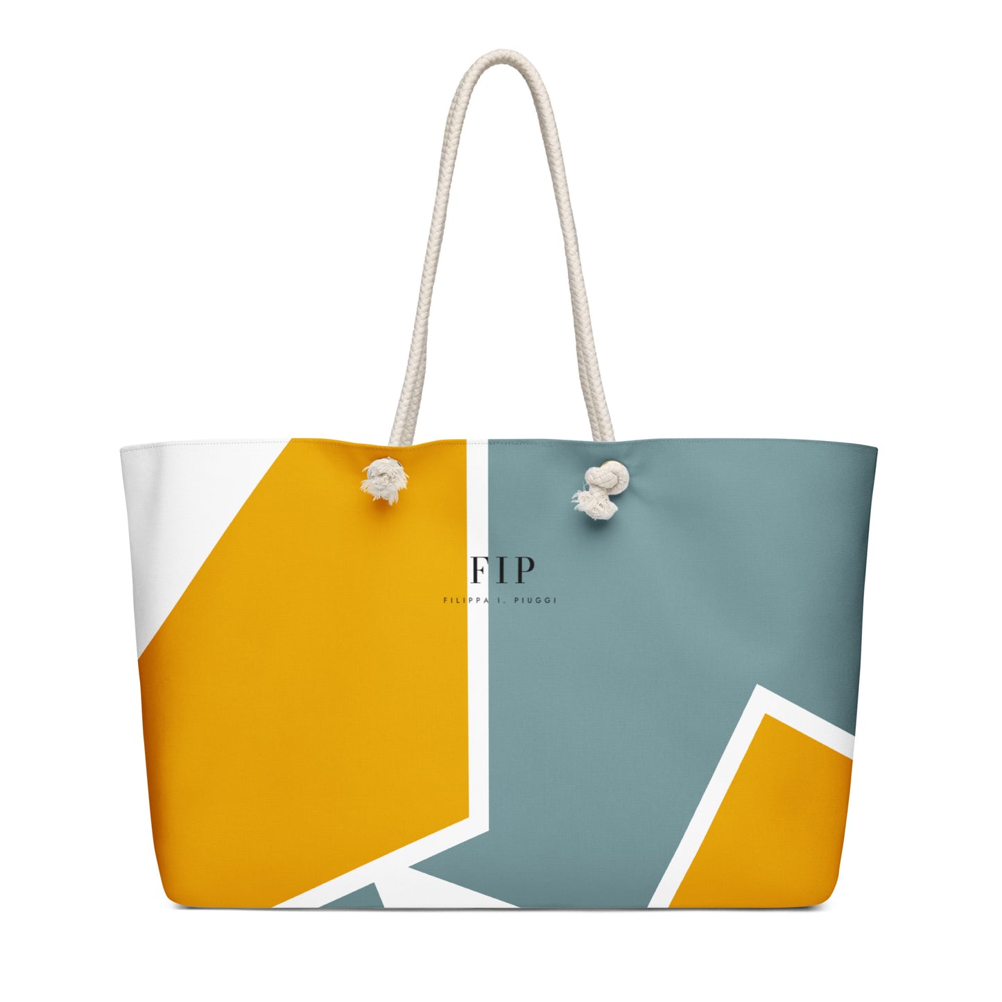 A tote bag with a modern geometric color-blocked pattern in mustard yellow, slate blue, and white, featuring off-white rope handles.