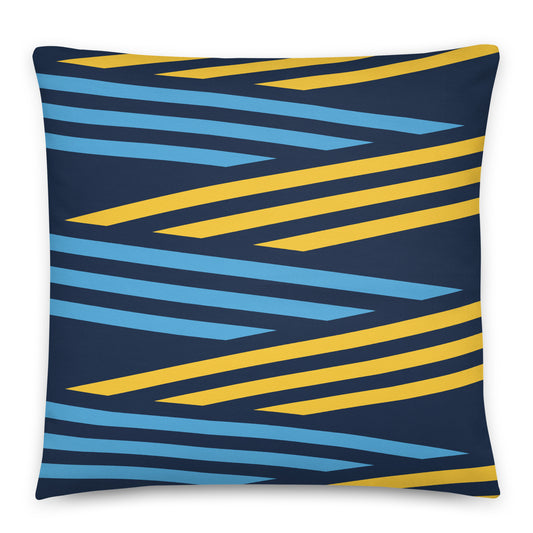 A square throw pillow featuring a modern geometric pattern of diagonal stripes in yellow and light blue on a dark navy blue background. 