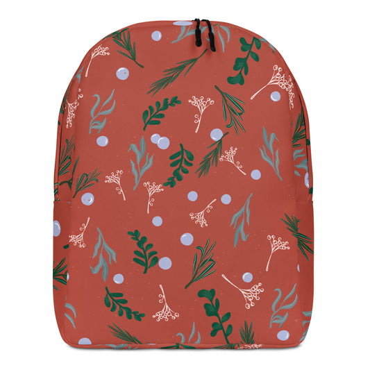 A drawstring backpack with a terracotta orange background and a festive botanical pattern featuring green pine branches, light blue berries, and pale pink holly leaves, 