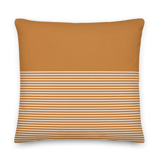 A square throw pillow in a warm camel brown color, featuring a horizontal band of thin white stripes across the lower half