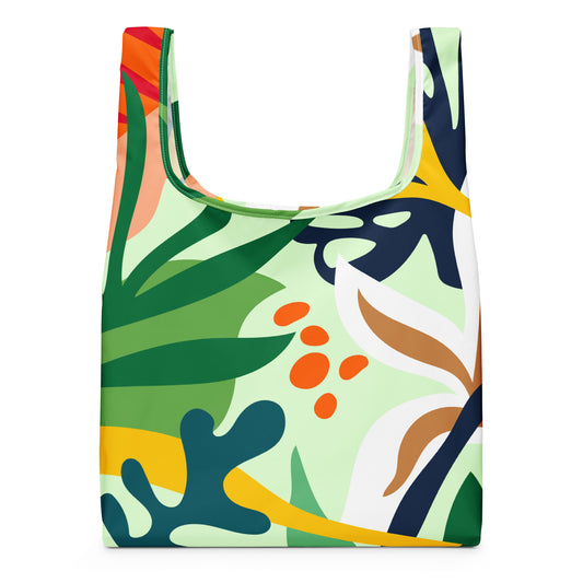 A reusable tote bag with a colorful abstract botanical print featuring green, navy, yellow, orange, white, and peach shapes. 