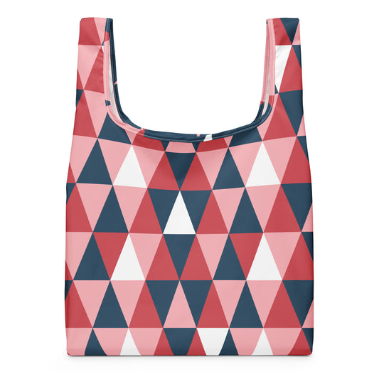 A reusable tote bag with a geometric triangle pattern in pink, red, navy blue, and white.