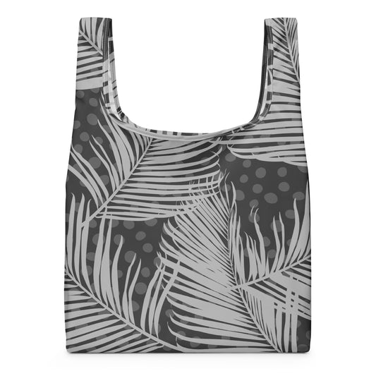 A reusable tote bag with a gray and white tropical palm leaf pattern and dark gray polka dots.