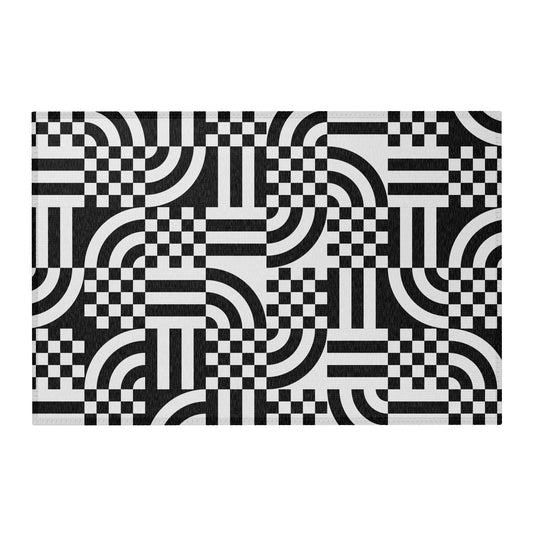A rectangular area rug with a bold black and white geometric pattern of checkered squares, arches, and stripes,