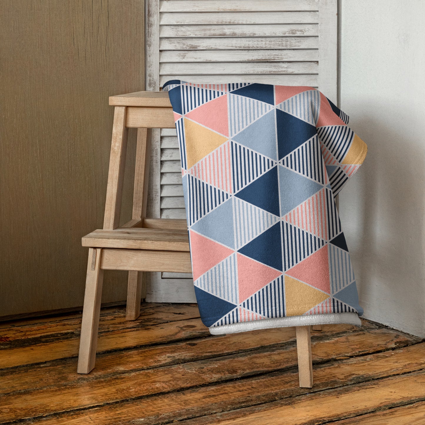 beach towel with a geometric triangle pattern in navy blue, dusty pink, light blue, and mustard yellow,