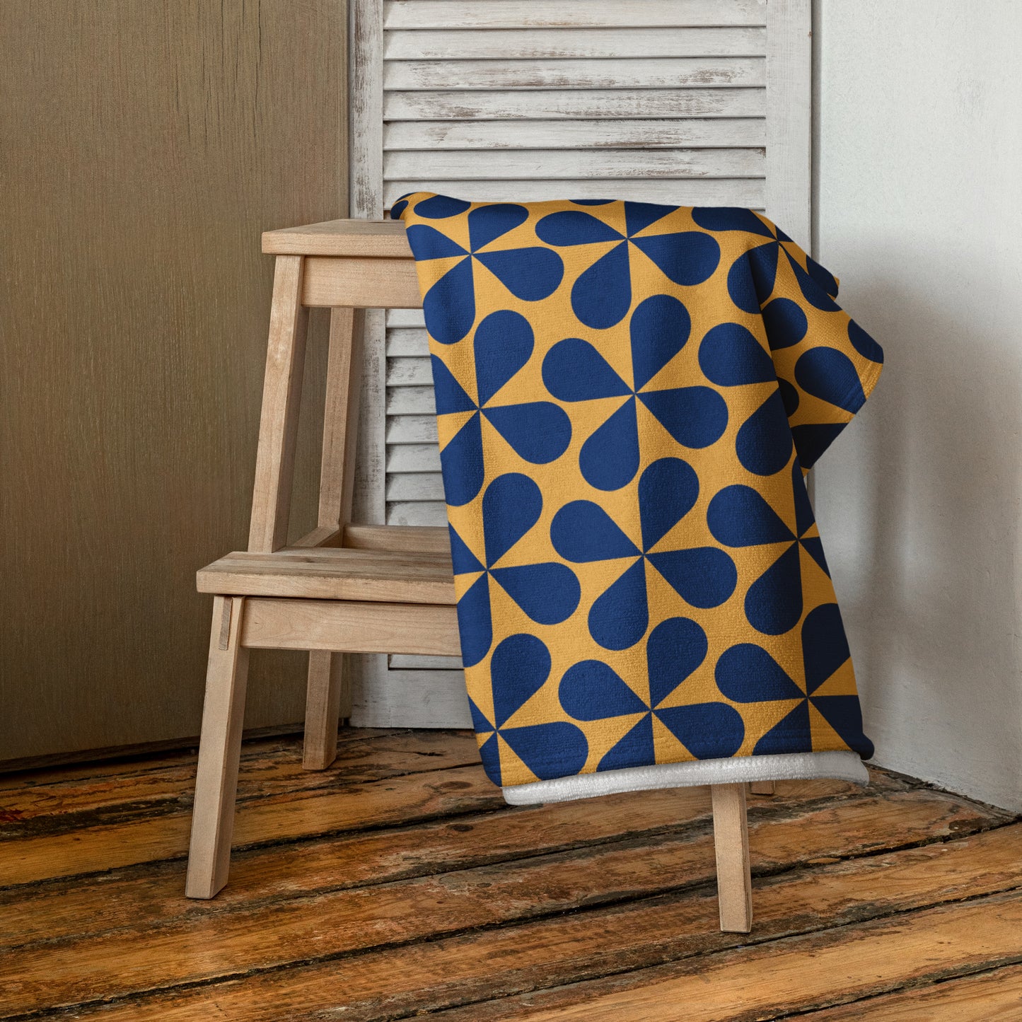 beach towel with a bold geometric pattern of navy blue and mustard yellow shapes draped 