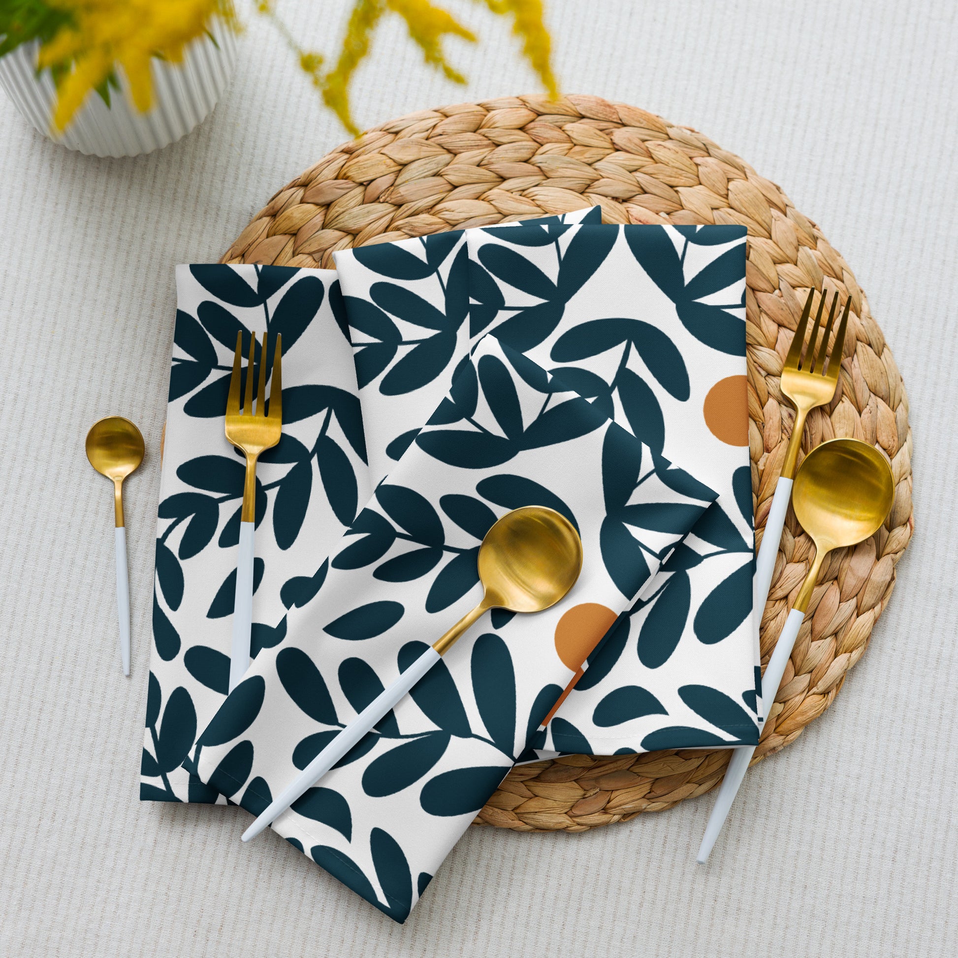 white cloth napkins with a dark teal leaf pattern and small yellow olives. 