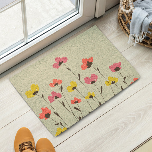 A rectangular doormat with a beige background and a pattern of pink, yellow, and orange flowers with dark brown stems. 