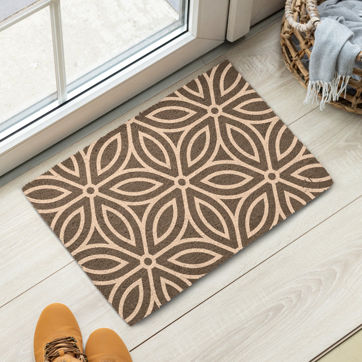 A rectangular doormat with a repeating geometric floral pattern in brown and beige. 