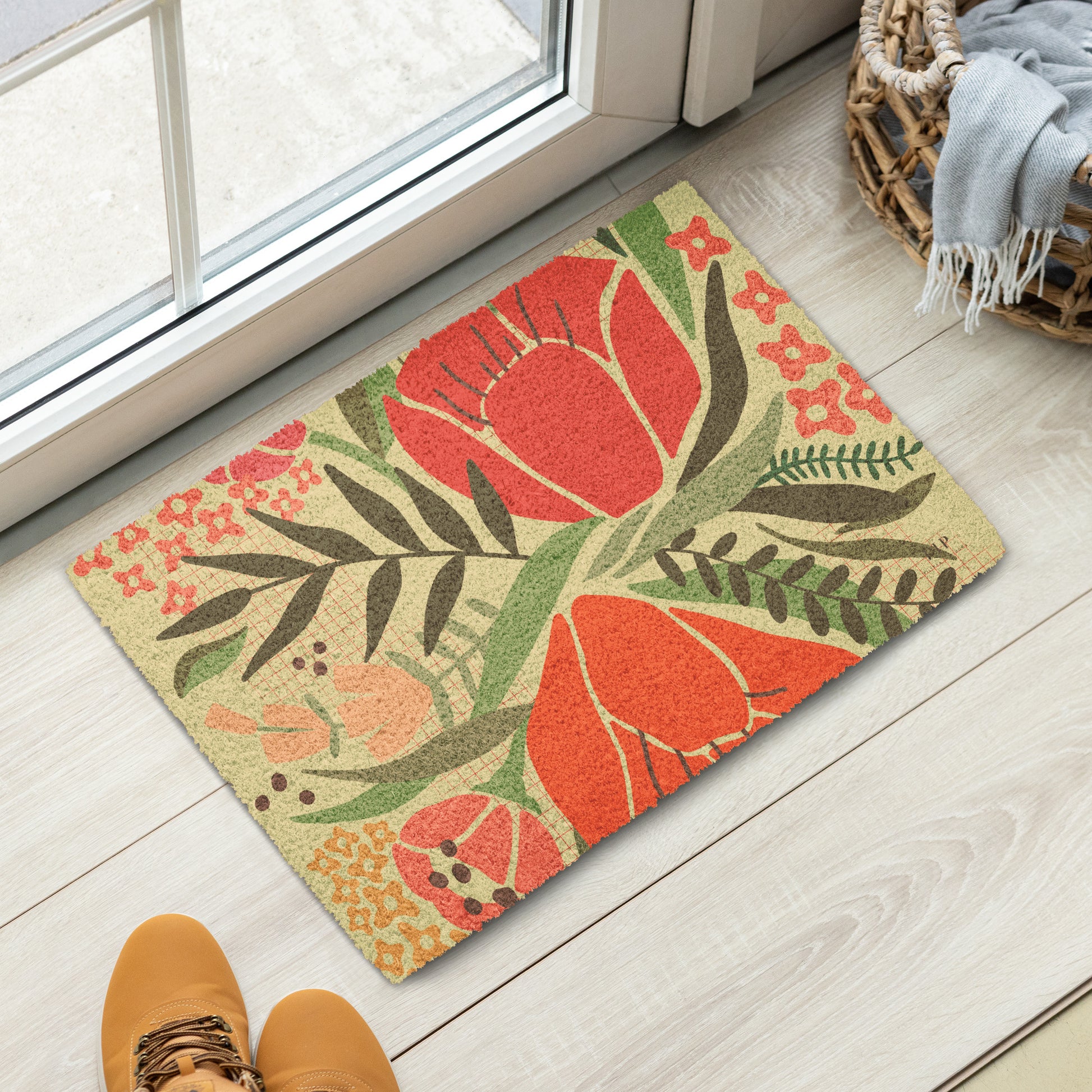 A rectangular doormat with a bold floral pattern in red, orange, green, and beige. 