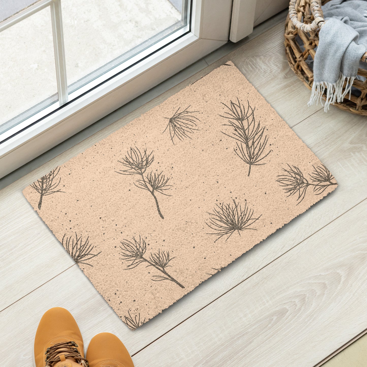 A rectangular doormat with a natural tan coir texture and a dark brown pine branch pattern