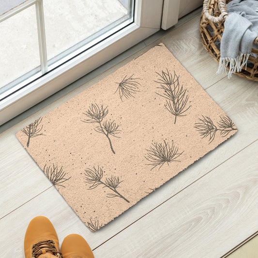 A rectangular doormat with a natural tan coir texture and a dark brown pine branch pattern