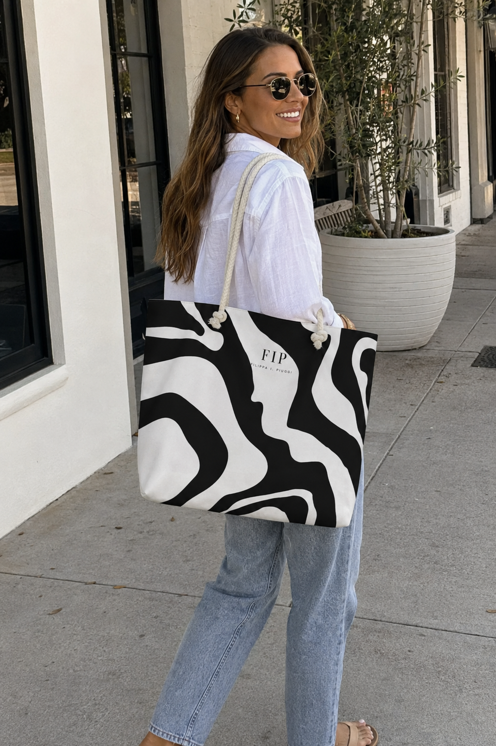 a large black and white marble 
zebra-print tote bag with cream handles on a city sidewalk.