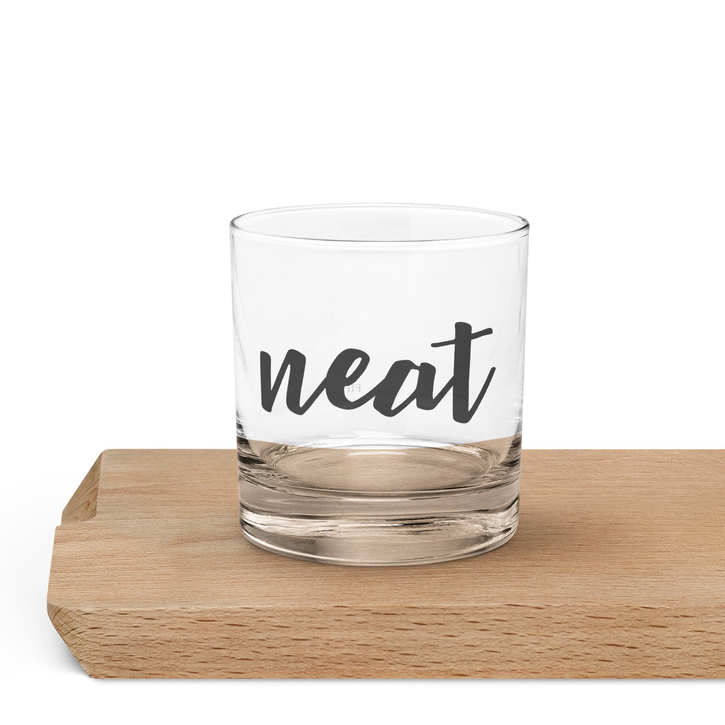 A clear glass rocks tumbler with the word 'neat' printed in black script.