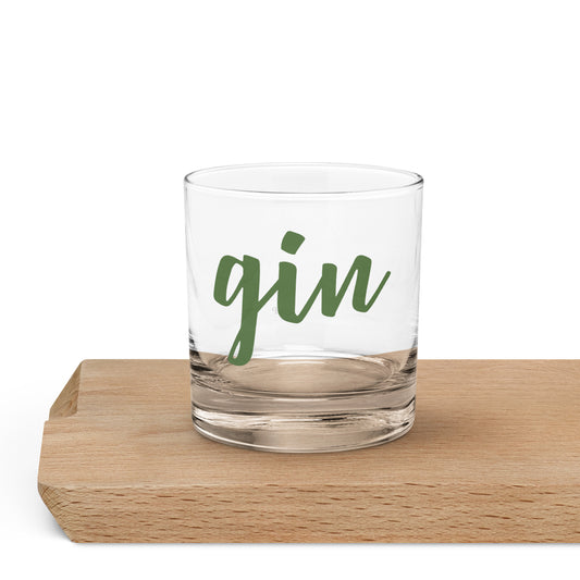 A clear glass rocks tumbler with the word 'gin' printed in green script.
