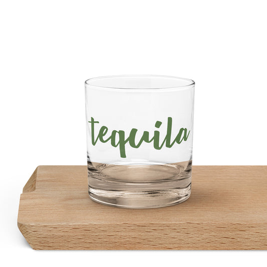 A clear rocks glass with the word 'tequila' printed in green script.