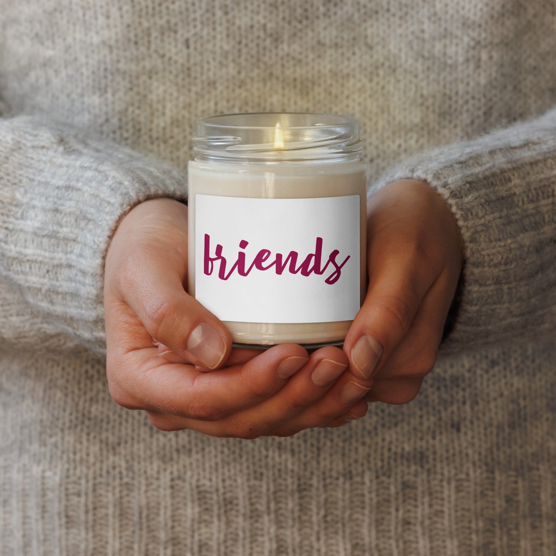 glass jar candle with a white label that reads 'friends' in dark pink script. soy scented candle