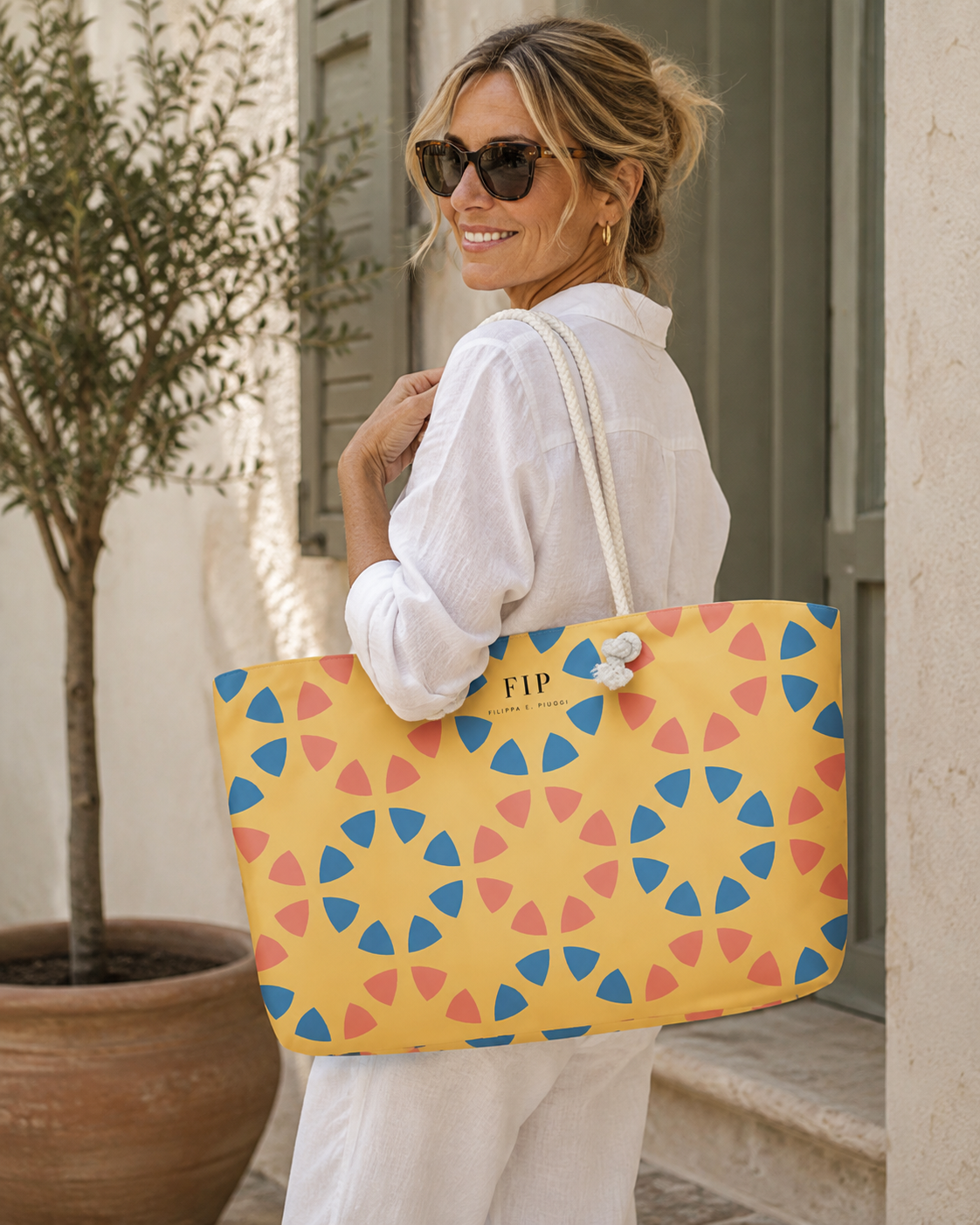 large yellow tote bag with a colorful geometric star pattern in blue and pink. The bag has a white rope handle 