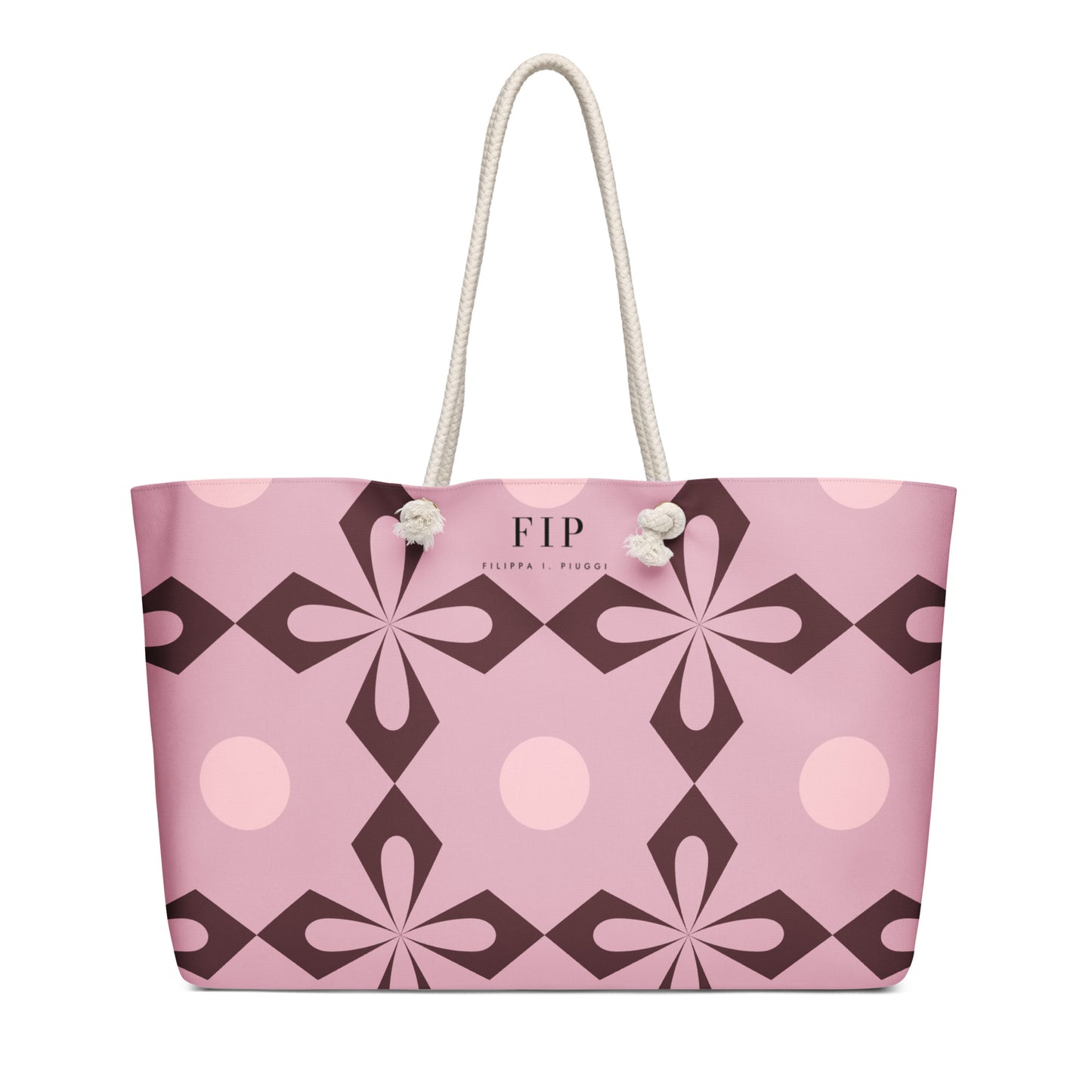 A pink tote bag with a geometric floral pattern in dark brown and light pink, featuring cream-colored rope handles. 