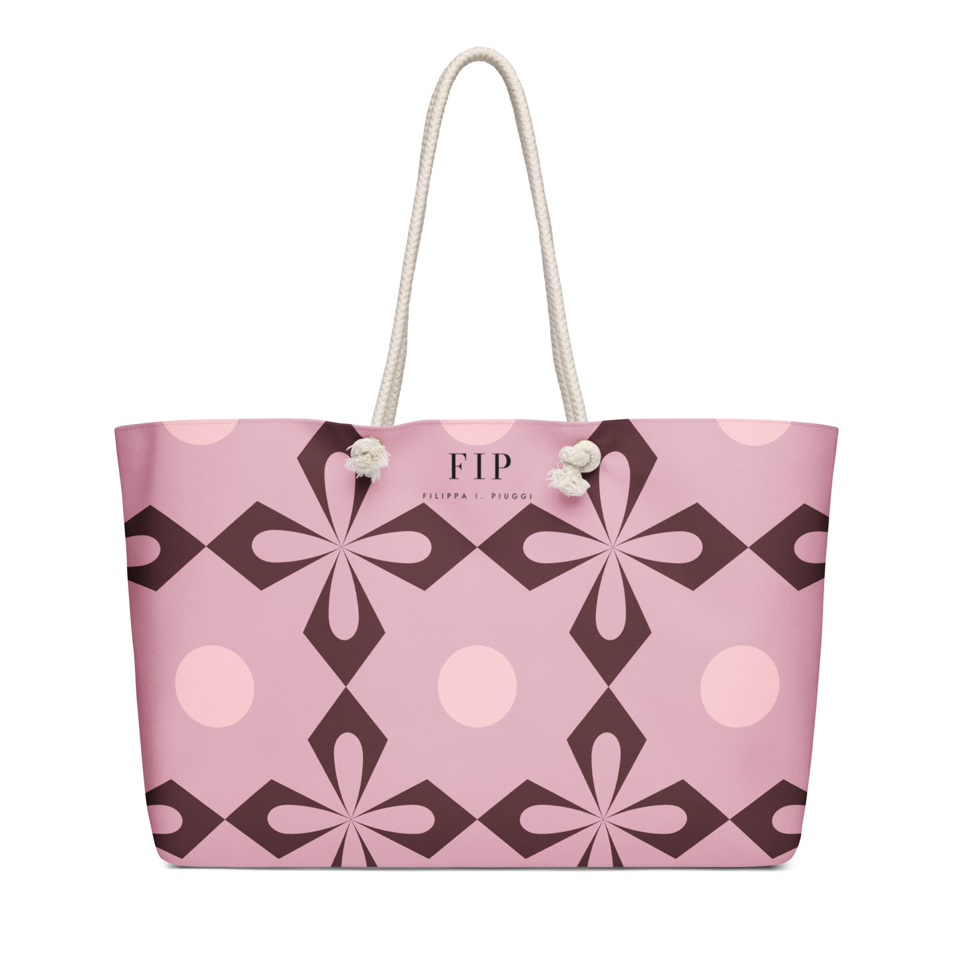 A pink tote bag with a geometric floral pattern in dark brown and light pink, featuring cream-colored rope handles. 