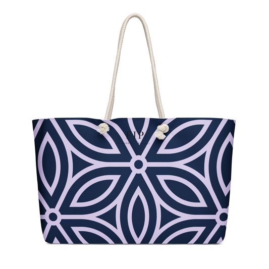 A tote bag with a navy blue and light purple geometric pattern, featuring thick off-white rope handles.