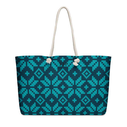 A tote bag with aztec pattern in teal and dark blue, featuring off-white rope handles. 