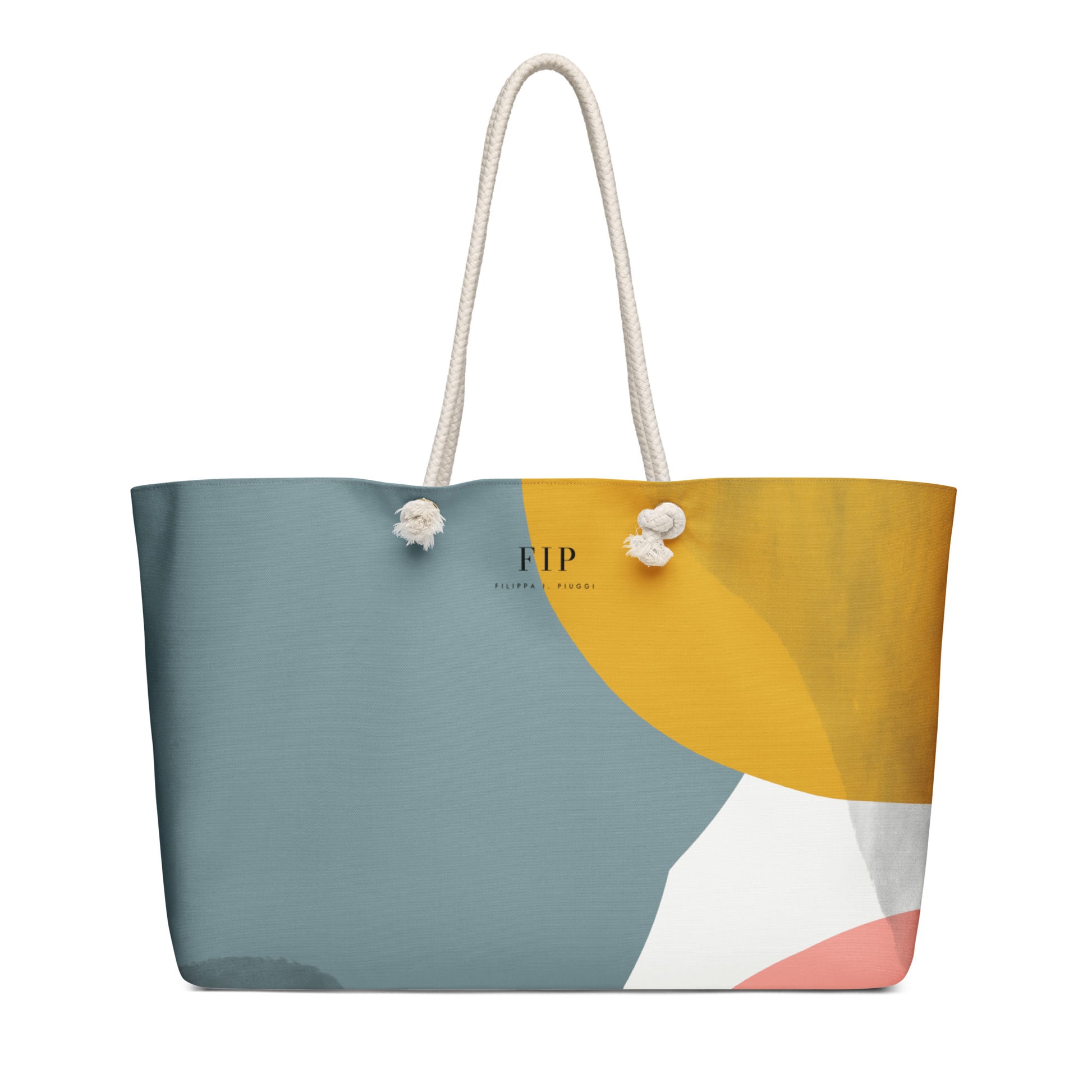 A tote bag with a modern abstract geometric design in slate blue, mustard yellow, white, and soft pink, featuring off-white rope handles.