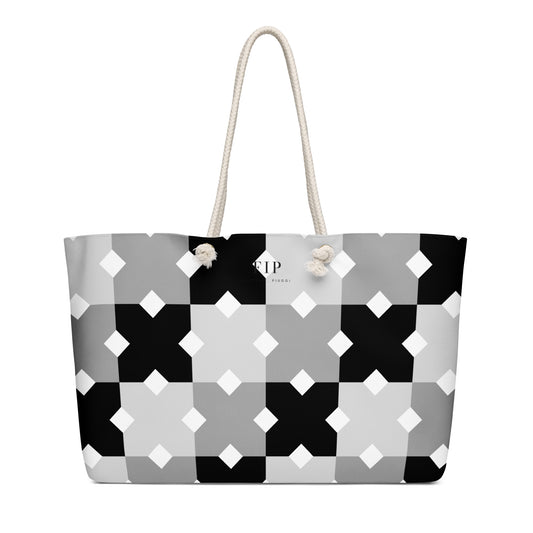 A tote bag with a geometric black, gray, and white pattern, featuring cream-colored rope handles 