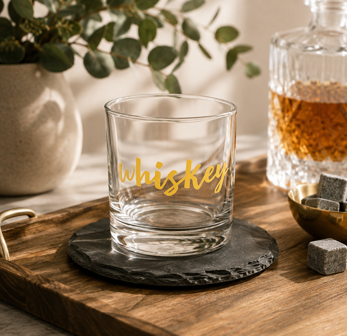 A clear glass whiskey tumbler with 'whiskey' written in gold script